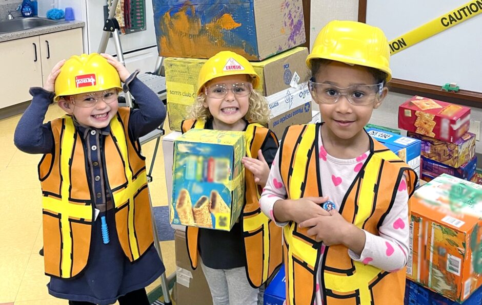 three girls in yellow hardhats and safety vests