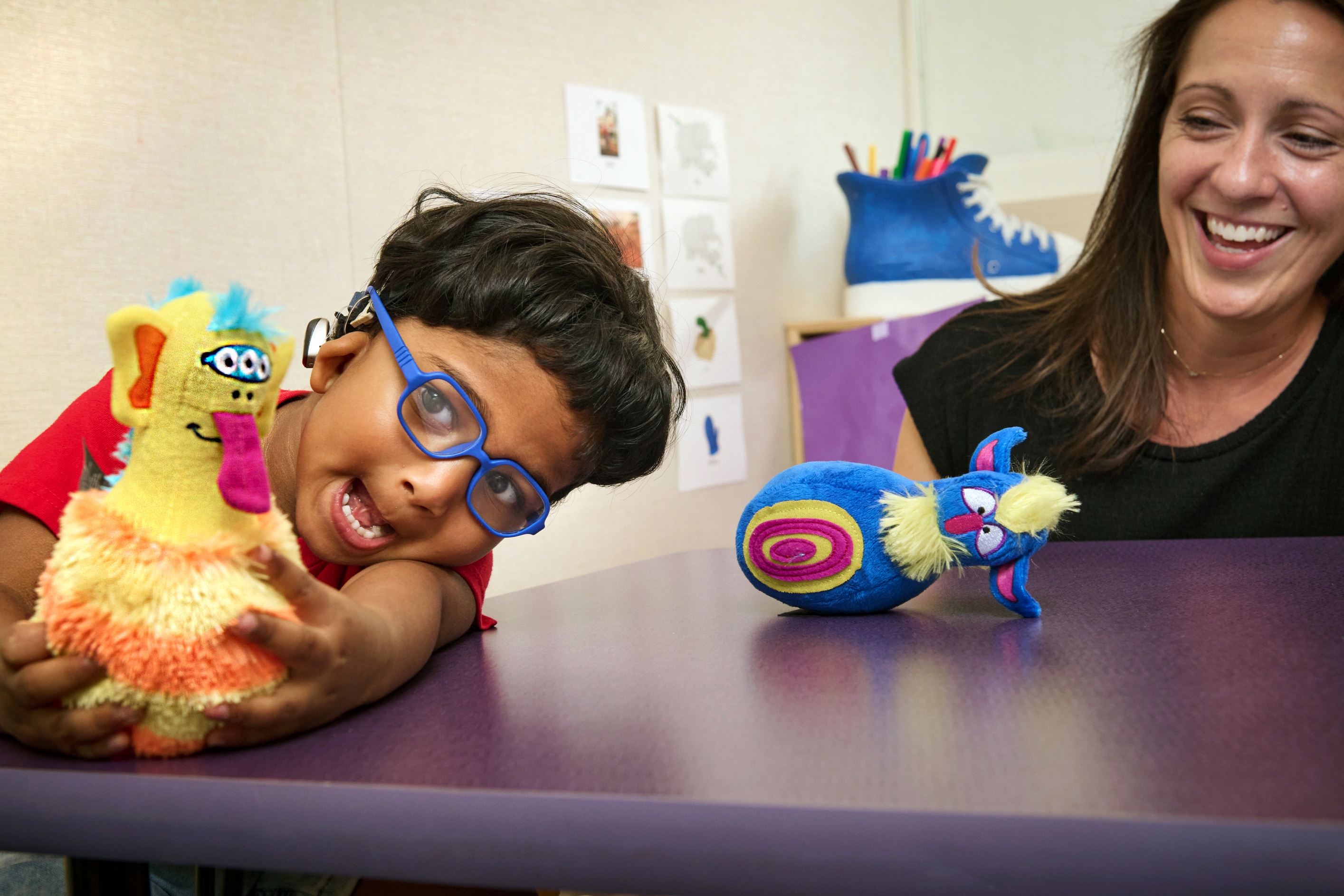 child acting silly with a goofy toy and his smiling teacher